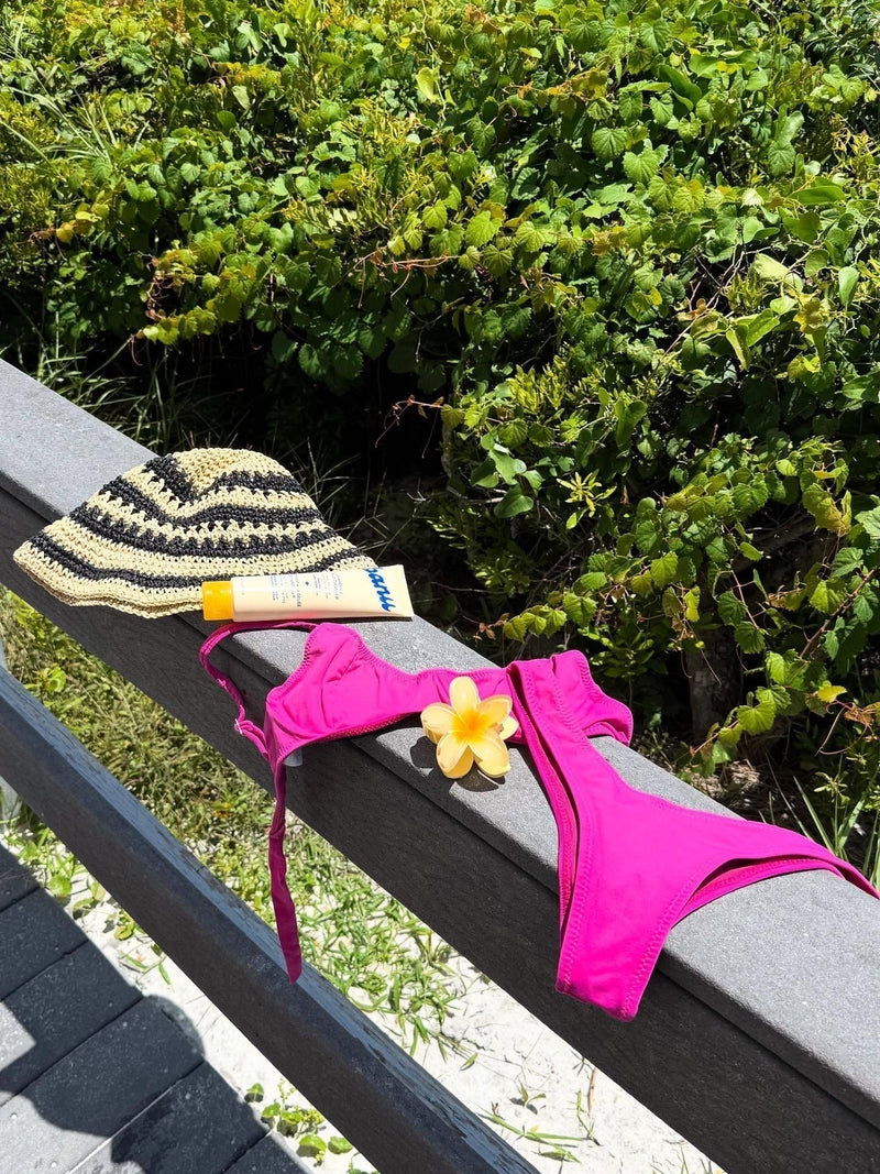 a magenta swimsuit, knit hat, and the chamomile jelly cleanser on a fence